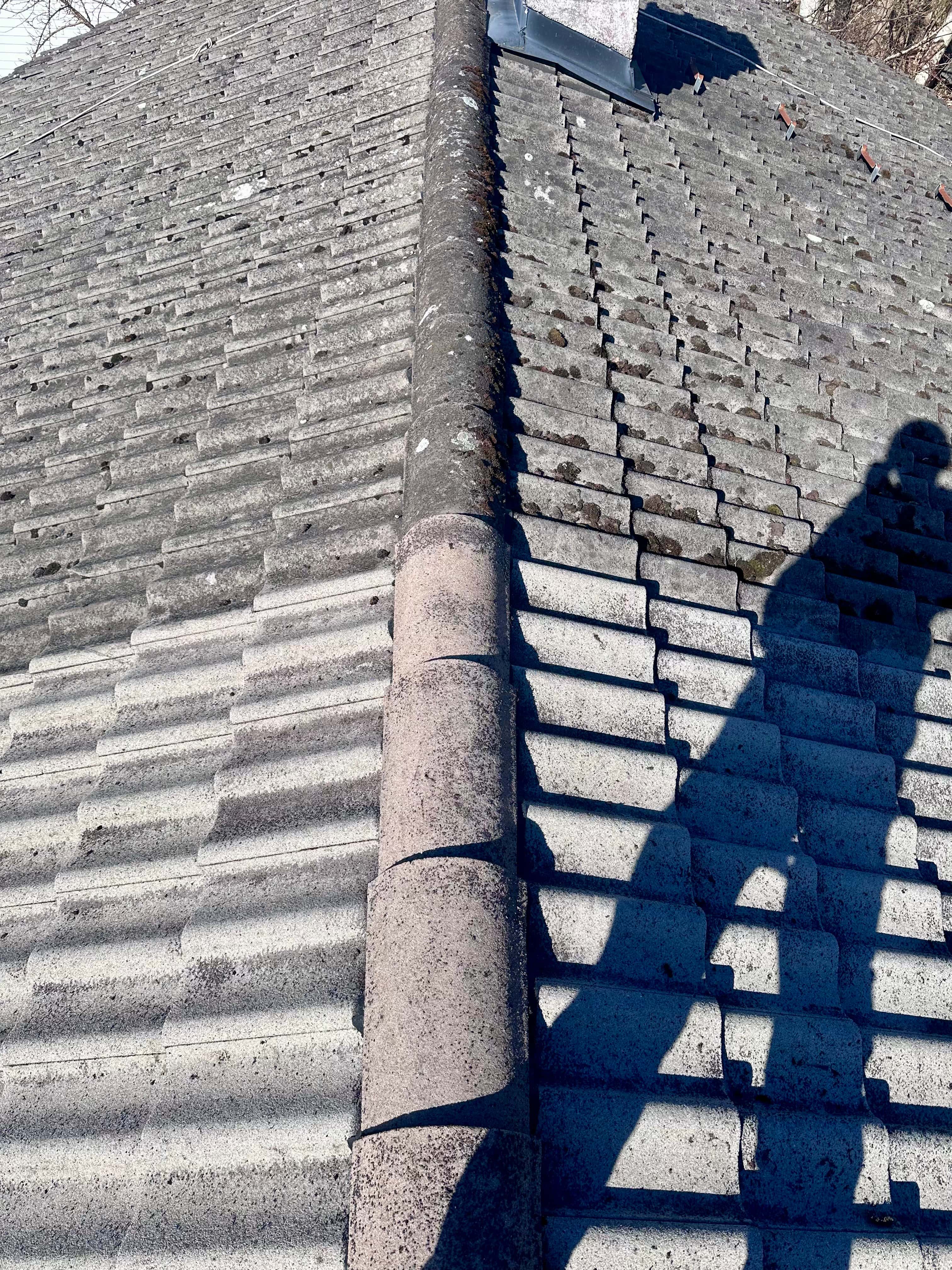 Roof cleaning in progress with visible pressure washing tool on red tiles
