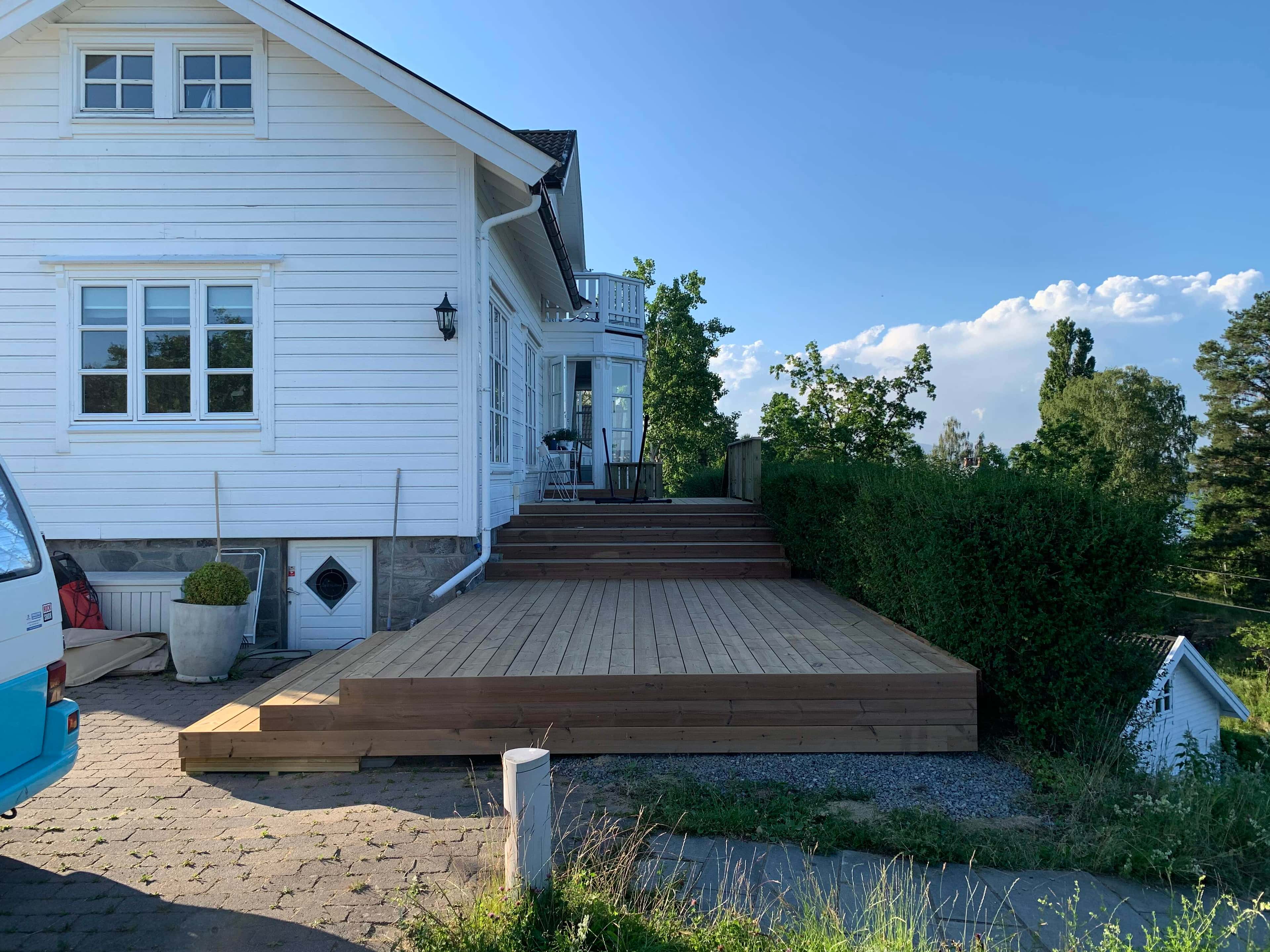 New wooden deck built around a small white and beige cottage